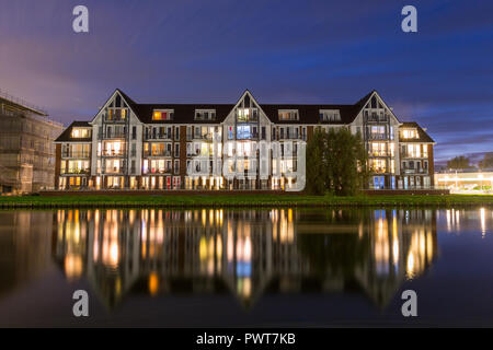 Reflexionen in einen Kanal eines modernen Wohnungen Gebäude mit bunten Lichter während der Blauen Stunde in Suburban Area in Holland. Stockfoto