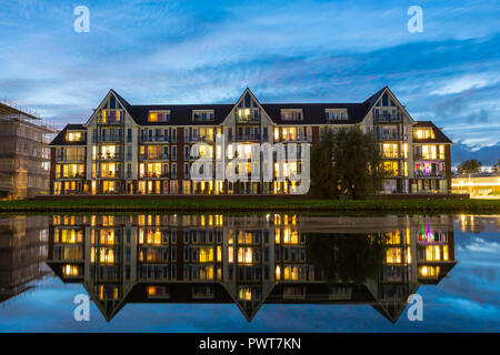 Reflexionen in einen Kanal eines modernen Wohnungen Gebäude mit bunten Lichter während der Blauen Stunde in Suburban Area in Holland. Stockfoto