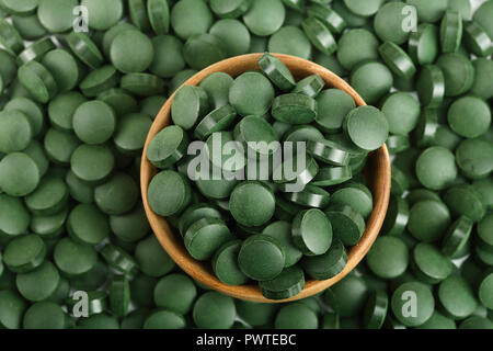 Haufen von Spirulina Tabletten Algen Nahrungsergänzungsmittel in Houten als Hintergrund Nahaufnahme, Ansicht von oben. Flach. Stockfoto