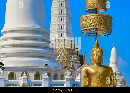 Eine große Buddha Statue steht vor der weißen Chedis in Wat Pichaiyat in Bangkok, Thailand, seine Hände in das abhaya oder Freiheit von Furcht Geste Stockfoto