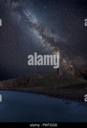 Atemberaubende leuchtende Milchstraße zusammengesetzten Bild über Landschaft von Dunstanburgh Castle auf der Küste von Northumberland in England Stockfoto