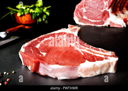 Frisch und rohes Fleisch roh chop Steak auf schwarzem Hintergrund aus schwarzem Schiefer. Gegrilltes und gebratenes Fleisch. BBQ Stockfoto