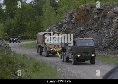 Us-Soldaten mit Echo Company, 186th Brigade Support Battalion, 86th Infantry Brigade Combat Team (Berg), Vermont National Guard, ein anderes Fahrzeug abzuschleppen am Fort Drum, N.Y., 19. Juni 2017. Die Soldaten wurden mit einer fiktiven IED Hit und hatte während einer Konvoi live fire Übung gezogen zu werden. Stockfoto