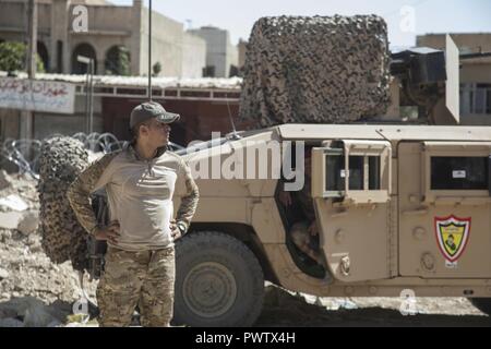 Eine irakische Sicherheitskräfte Mitglied sieht die Straße hinunter nach Festlegung eines neuen Patrol Base mit US-Soldaten in Mossul, Irak, 19. Juni 2017. Eine globale Koalition von mehr als 60 regionalen und internationalen Nationen haben sich zusammengeschlossen, um Partner Kräfte ISIS zu besiegen und die Stabilität und die Sicherheit wiederherstellen. CJTF-OIR ist die globale Koalition zu besiegen ISIS im Irak und in Syrien. Stockfoto