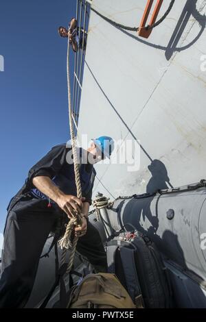 Arabischen Golf (20. Juni 2017) Engineman 3. Klasse Joshua Hohn, zugeordnet zu den Coastal Patrol Schiff USS Feuerblitz (PC 10), empfängt Sie das Zahnrad auf eine starre - Rumpf Schlauchboot aus der Geführten-missile Cruiser USS Vella Golf (CG72) während der Durchführung einer Bootsfahrt während der Übung Spartan Kopis 17. Übung Spartan Kopis ist eine Task Force (TF) 55 - LED-Übung zwischen der US Navy und der US-Küstenwache, um taktische Kenntnisse verbessern, erweitern und Ebenen der Zusammenarbeit, gegenseitige Unterstützung und langfristige Sicherheit und Stabilität in der Region erhöhen. Vella Golf ist in den USA der 5. Flotte eingesetzt werden Stockfoto