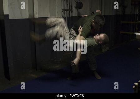 Cpl. Austin wirft Vilardi-Hawk Lance Cpl. Garett Verbrennungen beim Marine Corps Martial Arts Programm für die Ausbildung an Bord der USS Bonhmme Richard (LHD6) während in den Pazifischen Ozean, 22. Juni 2017 im Gange. Vilardi-Hawk ist ein militärischer Polizist und Martial Arts Instructor mit der Bekämpfung der Logistik Bataillon 31 und Verbrennungen ist ein Kampf Videofilmer mit dem 31 Marine Expeditionary Unit. MCMAP fördert die körperliche Eignung und Fähigkeiten schärft Marines im Nahkampf zu übergeben. Die 31. MEU Partner mit Amphibischen Squadron 11 der Marine den amphibischen Komponente von Bonhomme Richard Expeditionary Strike Group zu bilden. Stockfoto