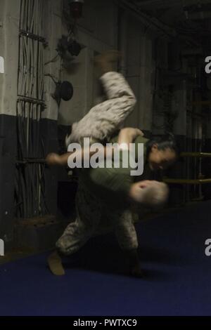 Cpl. Austin wirft Vilardi-Hawk Lance Cpl. Garett Verbrennungen beim Marine Corps Martial Arts Programm für die Ausbildung an Bord der USS Bonhmme Richard (LHD6) während in den Pazifischen Ozean, 22. Juni 2017 im Gange. Vilardi-Hawk ist ein militärischer Polizist und Martial Arts Instructor mit der Bekämpfung der Logistik Bataillon 31 und Verbrennungen ist ein Kampf Videofilmer mit dem 31 Marine Expeditionary Unit. MCMAP fördert die körperliche Eignung und Fähigkeiten schärft Marines im Nahkampf zu übergeben. Die 31. MEU Partner mit Amphibischen Squadron 11 der Marine den amphibischen Komponente von Bonhomme Richard Expeditionary Strike Group zu bilden. Stockfoto