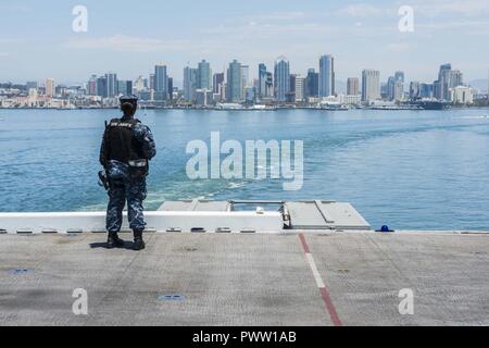 U.S. Navy's Aviation Bootsmann Mate (Handling) 2. Klasse Morgan Jackson, von Culver City, Calif., steht auf dem Flugdeck der USS Makin Island (LHD 8) als Amphibisches Schiff Hafen von San Diego 26. Juni 2017 Transite. Makin Island durchgeführten Operationen vor der Küste von Südkalifornien. ( Stockfoto