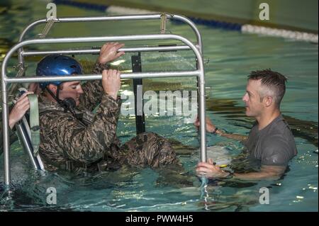 (Von links) Kapitän David Shadoin, 54 Helicopter Squadron Pilot, ist unterrichtet, die die Tech. Sgt. Clifton Cleveland, 5 Operations Support Squadron überleben, Steuerhinterziehung, Widerstand und Flucht Spezialist, während underwater Survival Training in Minot Air Force Base, N.D., 22. Juni 2017. Das seichte Wasser egress Trainer ermöglicht Flieger escape Verfahren während eines simulierten Absturz eines Hubschraubers zu üben. Stockfoto