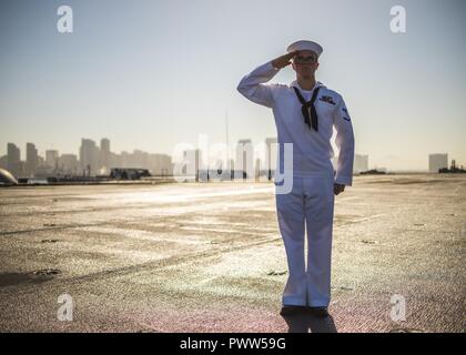 SAN DIEGO (27. Juni 2017) Operations Specialist 3. Klasse Benjamin Kirkpatrick, Mitglied der USS Carl Vinson (CVN 70) Color Guard, begrüßt den nationalen Ensign, wie es auf die Hälfte fliegt - Mast zu Ehren der sieben Seeleute, die an Bord der USS Fitzgerald umgekommen (DDG62) bei einem Zusammenstoß auf See. Carl Vinson ist pierside in ihren Heimathafen San Diego nach Abschluss einer fünf-und-ein-halb-Monat Bereitstellung in den Westpazifik. ( Stockfoto