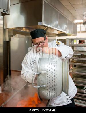 Maynard Oestreich, Executive Chef für Aramark Mahlzeiten bereitet vor der Flieger Führung Schulabschluss bei Travis Air Force Base, Calif., 28. Juni 2017. Oestreich einem ehemaligen US Navy Veteran und einem preisgekrönten Küchenchef aus Napa Valley, Calif., nahm der Küchenchef Position, so dass er Mentor junger Flieger könnte. Stockfoto