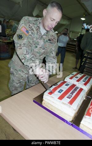 Colonel Elmer Holt, Stabschef der Gemeinsame Multinationale Ausbildung Group-Ukraine und der US Army 45th Infantry Brigade Combat Team, Feierlich schneidet den Kuchen, während Soldaten mit der 45th IBCT das Viertel von Juli feiern mit einer Grillparty und verschiedenen sportlichen Veranstaltungen an der Yavoriv Combat Training Center auf dem internationalen Friedens und der Sicherheit, in der Nähe der Yavoriv, der Ukraine, der am 4. Juli. Der 45 IBCT ist in der Ukraine als Teil des Gemeinsamen multinationalen Ausbildung Group-Ukraine, eine internationale Koalition für eine Verbesserung der Ausbildung der Fähigkeit des CTC und Gebäude professionali bereitgestellt Stockfoto