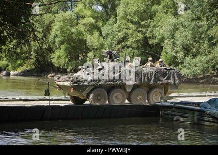 Soldaten zur 1. Staffel, 2d-Cavalry Regiment, US-Armee zugewiesene Laufwerk ihre Stryker bekämpfen Fahrzeug über den Mosoni-Duna Fluss in Györ, Ungarn auf einem PMP schwimmende Brücke während der Übung Szentes Ax 17. Juli 4, 2017. Die Brücke emplaced wurde von den Ingenieuren der 37th Engineer Regiment, Ungarische Verteidigung und Feuerwehr 837th Engineer Battalion, U.S. Army National Guard von Wooster, Ohio. Die Ungarische Nationale Bewegung findet statt am 26. Juni - 7. Juli Sabre Guardian 17 durch taktische Bridging und Wasser Kreuzung Operationen für 2CR Bewegungsfreiheit von zu Hause station in Ungarn zu können. Stockfoto