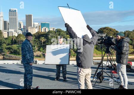 SYDNEY (1. Juli 2017) Kapitän Larry McCullen, kommandierender Offizier der Amphibisches Schiff, die USS BONHOMME RICHARD (LHD 6) spricht mit den Gastgebern 9 Nachrichten, eine australische Fernsehen morgen zeigen, aus dem Schiff Flight Deck während einer Live-Übertragung. Bonhomme Richard machte einen Port zu Sydney als Teil der Talisman SABRE 2017, der eine zweijährige USA - Australien bilaterale militärische Übung, verbindet ein Feld Training und Kommandostellenübung Interoperabilität und zur Stärkung der Grundsätze der amerikanisch-australische Bündnis zu wahren. Stockfoto