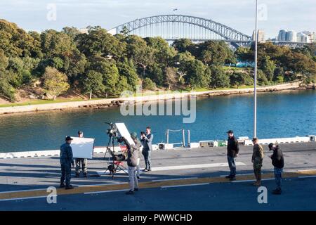 SYDNEY (1. Juli 2017) Kapitän Larry McCullen, kommandierender Offizier der Amphibisches Schiff, die USS BONHOMME RICHARD (LHD 6) spricht mit den Gastgebern 9 Nachrichten, eine australische Fernsehen morgen zeigen, aus dem Schiff Flight Deck während einer Live-Übertragung. Bonhomme Richard machte einen Port zu Sydney als Teil der Talisman SABRE 2017, der eine zweijährige USA - Australien bilaterale militärische Übung, verbindet ein Feld Training und Kommandostellenübung Interoperabilität und zur Stärkung der Grundsätze der amerikanisch-australische Bündnis zu wahren. Stockfoto