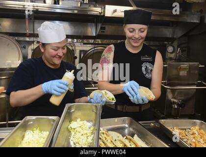 SURIGAO STRAIT (4. Juli 2017) Kulinarische Specialist 1. Klasse Nora Velazquez, links, von Richmond, Virginia, und Lance Cpl. Angelica Baker, von Temecula, Kalb, Fisch Tacos an Bord der Flugzeugträger USS Nimitz (CVN 68), 4. Juli 2017, in der Sulu See. Der Nimitz ist derzeit auf Einsatz in den USA 7 Flotte Bereich der Operationen. Die US-Marine hat die Indo-Asia Pacific routinemäßig Seit mehr als 70 Jahren die Förderung von Frieden und Sicherheit in der Region patrouillierte. ( Stockfoto