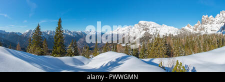 Panoramablick von frischem Pulver in die Wälder, schneebedeckte Berge und im Tal unten. Italienische Alpen Winter, blauer Himmel und einige große Schneeschuhwandern. Stockfoto