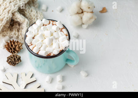 Blau metall Tasse Kakao oder eine heiße Schokolade mit Marshmallows auf dem Tisch mit Winter Dekor, Zweig der corton Blume, gestrickte Decke und Holz- Christm Stockfoto