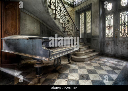 Innenansicht der Flur mit einem großen Klavier und einer Treppe in einer verlassenen Villa in Frankreich. Stockfoto