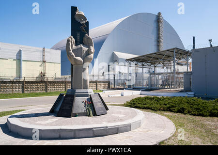 Blumen am Denkmal vor dem Sarkophag, der Stahl- und Betonbau, die den nuklearen Reaktor Nr. 4 in Tschernobyl, Ukraine. Stockfoto