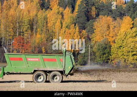 Salo, Finnland - 14. Oktober 2018: Bergmann Dungstreuer durch Schlepper bei der Arbeit im Feld der Schnitthöhe an einem schönen Tag im Herbst gezogen. Stockfoto