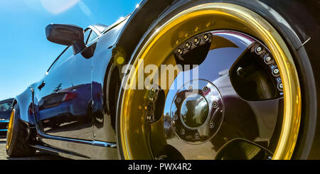 Refkective schwarzes Auto mit Gold und Schwarz Reifenfelge Stockfoto