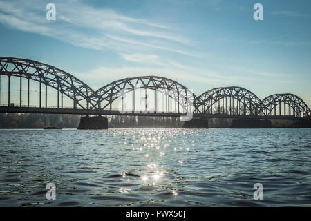 Eisenbahnbrücke in Riga über den Fluss Daugava im Herbst im Oktober an einem sonnigen Tag, Landschaft Stockfoto