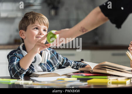 7/8 Schoß von Mutter, green apple zu ihrem Sohn während er Hausaufgaben Stockfoto