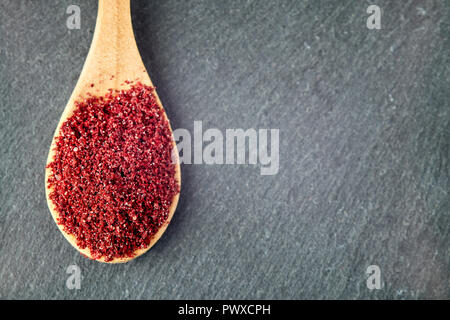 Boden sumac Spice Pulver in Löffel aus Holz. Ansicht von oben mit der Kopie Raum Stockfoto