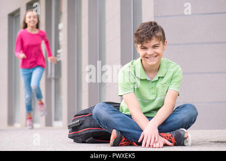 Glückliche Kinder - Jungen und Mädchen mit Rucksack auf den ersten oder den letzten Schultag - Outdoor Portrait. Aufgeregt zurück in die Schule nach dem Urlaub. Stockfoto