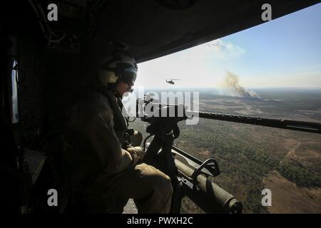 NORTHERN TERRITORY, Australien - US Marine Cpl. Tannyr Novak, Crew Chief, Marine Light Attack Helicopter Squadron 367, Marine Drehkraft Darwin, nimmt in der Ansicht während des Fluges zu einer Antenne gun Angebot am Berg Bundey Training Area, 21. Juni 2017. Während der Ausbildung, Piloten und Besatzungsmitglieder genau engagierte Ziele mit geführten Raketen, M2 .50 Kaliber Maschinenpistole und M240B Medium Maschinengewehr aus einer UH-1Venom. Novak ist aus Nashville, Illinois Stockfoto