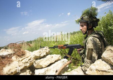 Eine ukrainische Soldaten bis zum yavoriv Combat Training Center Gegenkraft Einheit zugeordnet sein Feuer beobachtet, gerade für die Annäherung an die Soldaten vom 1. der ukrainischen Armee Airmobile Bataillon, 79 Air Assault Brigade während ein Bataillon Kraft - Kraft der Übung, die als Schlußstein des Bataillon während der Ausbildung an der Yavoriv CTC auf der internationalen Friedens und der Sicherheit, in der Nähe der Yavoriv, der Ukraine, der am 29. Juni. Stockfoto