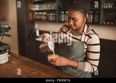 Lächelnden jungen afrikanischen Barista, eine frische Tasse Cappuccino Stockfoto