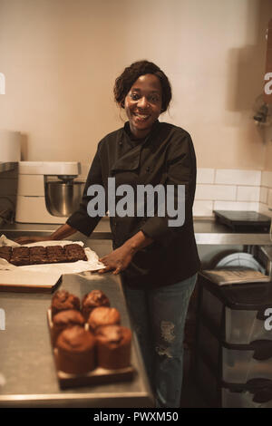 Lächelnd Bäcker an der Theke einer gewerblichen Küche arbeiten Stockfoto