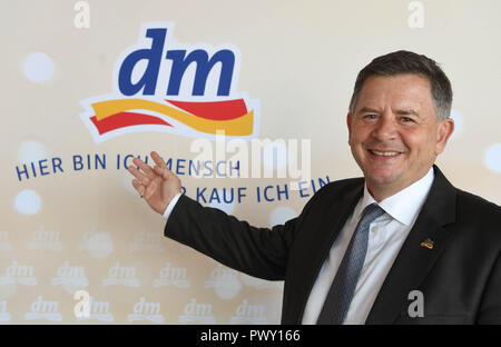 Karlsruhe, Deutschland. Okt, 2018 18. Erich Harsch, Vorsitzender der Geschäftsführung der Drogeriemarktkette dm, weist auf eine dm-Logo in Karlsruhe vor Beginn der Bilanzpressekonferenz der Apotheke Gruppe. Credit: Uli Deck / dpa/Alamy leben Nachrichten Stockfoto