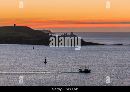 Roches Point, Cork, Irland. 18. Oktober, 2018. Ein kleines Fischerboot Köpfe aus Cork Harbour vor Sonnenaufgang das Bestehen der Roches Point Lighthouse, Co Cork, Irland Quelle: David Creedon/Alamy leben Nachrichten Stockfoto