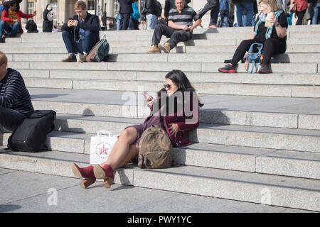 London, Großbritannien. 18. Oktober 2018. UK Wetter: eine Frau entspannen im Herbst Sonnenschein und warme Wetter in Trafalgar Square Credit: Amer ghazzal/Alamy leben Nachrichten Stockfoto