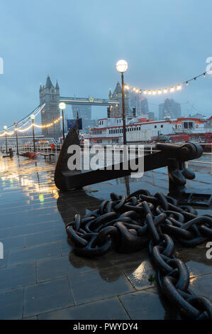 Ein nasser am frühen Abend auf Butlers Wharf mit den Dixie Queen Raddampfer, der Große Kette und Anker, Tower Bridge auf der South Bank der Themse London UK Stockfoto