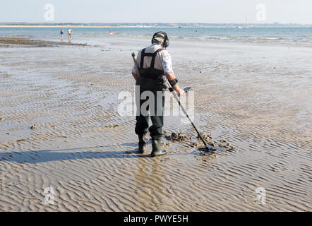 Männliche detectorist mit Metalldetektor bei Ebbe, Sandstrand Studland Bay, Swanage, Dorset, England, Großbritannien Stockfoto