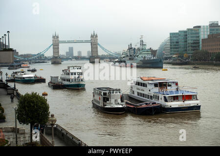 Touristische und Party Boote in der Themse mit HMS Belfast und der Tower Bridge im Hintergrund London England United Kingdom UK Stockfoto