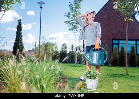 Lachende Frau mit Denim Shorts Holding großer Garten Sprinkler Stockfoto