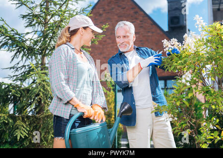 Paar pflege Gärtner in der Nähe von ihren schönen Strauch mit weißen Blumen Stockfoto