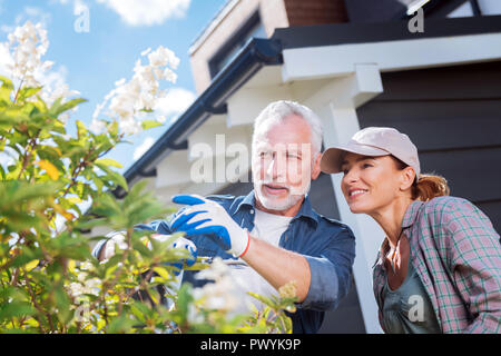 Paar erfolgreiche Geschäftsleute sehen, wie Ihr Baum im Garten blühen Stockfoto