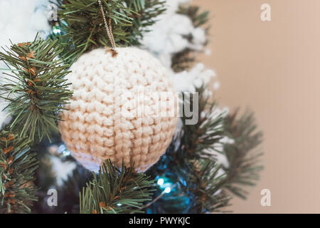 Weihnachtsbaum mit gestrickten weiße Kugel als Dekor mit Kopie Speicherplatz auf unscharfen Bokeh. Close Up. Stockfoto