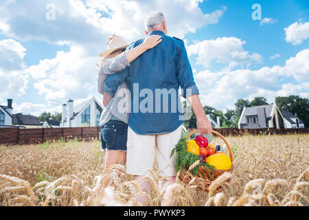 Liebespaar stehend auf dem Feld in der Nähe von ihr Kleines freistehendes Haus Stockfoto