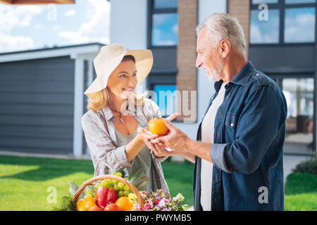 Pflege blonde Frau, die schöne frische Tomaten ihren bärtigen Mann Stockfoto