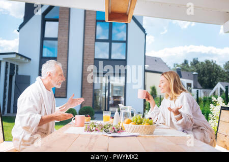 Glücklich strahlenden Paar emotionalen Gespräch, während Sie Ihr Frühstück essen Stockfoto