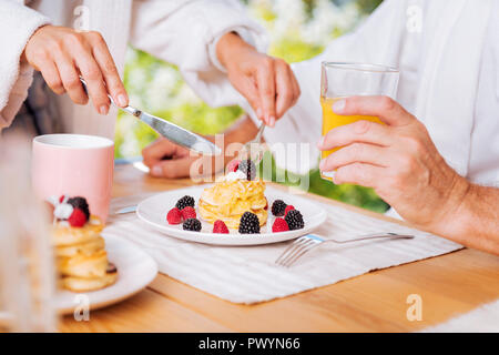 Reifer Mann in schönen, warmen Pfannkuchen mit Honig und Beeren für das Frühstück Stockfoto