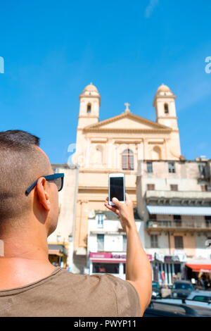 Nahaufnahme eines jungen kaukasischen Mann mit Sonnenbrille, ein Bild von der Kirche Saint-Jean-Baptiste, in der Altstadt von Bastia, Korsika, Frankreich Stockfoto