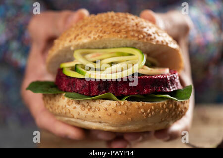 Nahaufnahme eines jungen kaukasischen Mann mit einem zuckerrüben burger Sandwich in der Hand Stockfoto